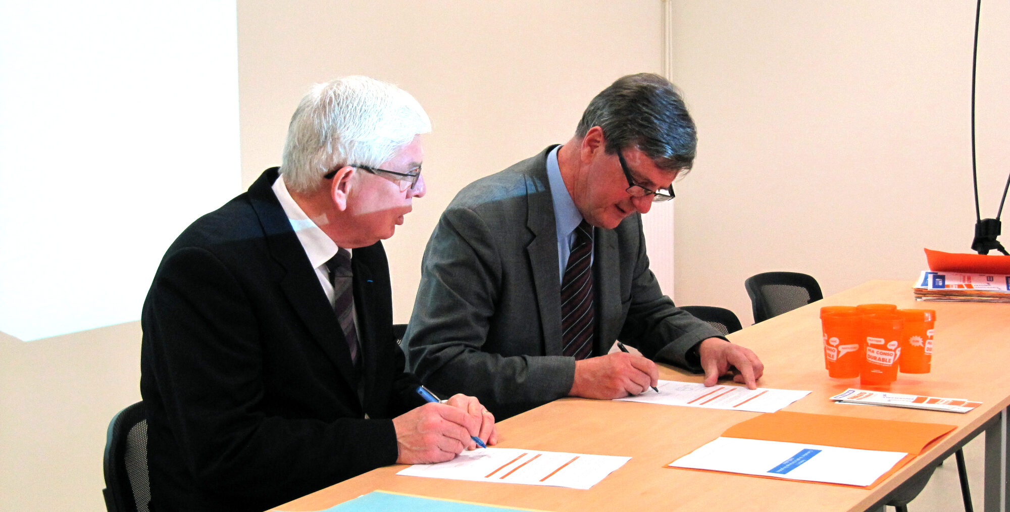 Les présidents de VALODEA et de l’AAPH signent la convention de partenariat, des gobelets réutilisables posés sur la table